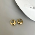 Close-up of polished gold-plated drop earrings on a minimalist grey background - Chunky Waterdrop Hoop / Gold