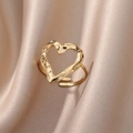 Detail of golden heart-shaped open ring with lava texture on champagne silk background - Gold Hollow Heart
