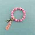 Vue détaillée d'un porte-clés à perles roses avec accents dorés et pompon doux - Rose