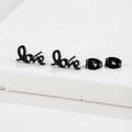 Close-up of black metal 'love' script stud earrings with matching butterfly backings - 128 Love / Black