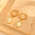 Detail view of 18k gold earrings with teardrop white shell pendants on textured stone - Water Drop Earrings