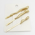 Close-up of three golden wave-shaped metal hair clips on a white display card - 3-Piece Set / Matte Gold