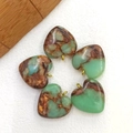 Cinq pendentifs cœur en turquoise avec attaches dorées sur fond blanc texturé - Peau de Serpent Cuivre Doré