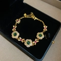 Detail of 24K gold plated bracelet with green gems and flower links in a velvet box - Gold-Green