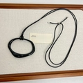 Gros plan du pendentif noir irrégulier sur cordon cuir dans un plateau à bijoux en bois - Noir
