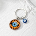 Detail eines Glas-Schlüsselanhängers mit blauem und orangefarbenem Auge des Teufels - 2# Brauner Boden Blaues Auge