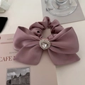 Detailed shot of pink satin bow scrunchie with a sparkling rhinestone heart center - Lotus Pink