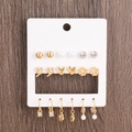 Set of 9 gold earrings with pearls and rhinestones on card over wooden background - 9 Pairs Pearl Heart Twist Flower Earring Set