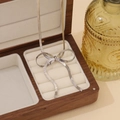 Detail of silver bow pendant on flat snake chain resting in a vintage wooden jewelry box - Silver Necklace