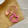 Close-up of pink flower keychain with small bell on vintage newspaper background - Pink