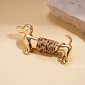 Close-up of golden dachshund brooch with brown braided rope texture on beige background - Gold