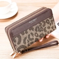 Detail of leopard print long wallet featuring double zippers and a leather wrist strap - Leopard Print With Brown Leather