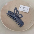Macro detail of large grey-blue butterfly hair claw clip on a ceramic tray - Gray