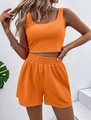 Dettaglio del set due pezzi in maglia a coste arancione con crop top smanicato e pantaloncini - arancio-rosso