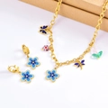 Detailed view of gold necklace and earrings set with blue flowers and dragonfly charms - Necklace + Earrings