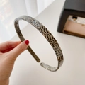 Minimalist acetate hairband with a brown and grey checkered pattern held by hand - Black Check