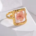 Detalle de anillo dorado con una flor seca rosa en un marco cuadrado de resina martillada - Forma Cuadrada de Flor Rosa de Cinco Pétalos (OLBR703-D-fen)