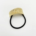 Detail of golden hammered metal plate on black elastic hair tie with reflective texture - Wrinkled Gold Rhombus