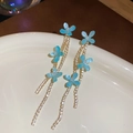 Detailansicht der blauen Harzblumen-Quastenohrringe mit Zirkonia auf weißer Keramik - S925 Silber Nadel / Blau