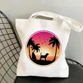 White canvas tote bag featuring sunset beach dog silhouette print on a black metal chair - C5 Beach Sunset Dog