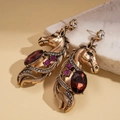 Detail van vintage paardenhoofdoorbellen met rode edelstenen en paarse strass-steentjes - Antiek Goud (Zilveren Naald)
