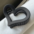 Pinza de pelo negra mate con forma de corazón y diseño calado sobre fondo gris rugoso - Aprox. 6,5 cm / Corazón Negro