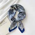 Silk-feel square scarf with blue paisley pattern tied in a bow on a white background - Paisley Small Border Navy