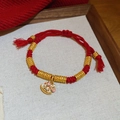 Macro shot of a red braided rope bracelet with golden beads and white enamel horse charm - 3# Bracelet-Gold-Red (White Rocking Horse)