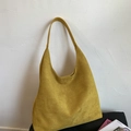 Sac à bandoulière HOBO minimaliste en daim jaune pour femme contre un mur texturé blanc - Avec sac intérieur / Jaune