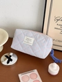 Close-up of quilted checkered makeup bag with blue zipper pull and cosmetic accessories - Octagonal Bag (Small) / Pink