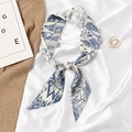 Blue and white silk skinny scarf tied in a bow on beige knitwear background - Letter W - Blue White Geometric Pattern