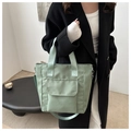 Detail of light green waterproof nylon tote bag worn with a black coat for daily commute - Green