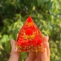 Pyramide d'énergie en cristal avec pierres rouges et lotus doré tenue à la main - Style 21