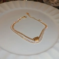 Détail d'un bracelet double couche doré avec zircons carrés et finition brillante - Bracelet double couche doré