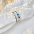 Detail of silver rings set with blue sapphire stone and star motif on white silk background - Two-Piece Set / Silver/Blue