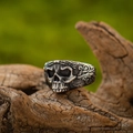 Vintage silver skull ring with gothic scrollwork engraving on a wooden texture background - Scrollwork Side Decor Skull