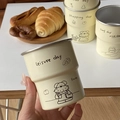 Close-up of a hand holding an off-white stainless steel dog doodle camping mug outdoors - Reading Dog