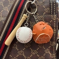 Detailed view of mini baseball keychain with bat, ball and glove on a brown bag strap - 白球桔色