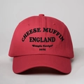 Close-up of black Cheese Muffin 1975 embroidery on a red cotton baseball cap - One Size / Red
