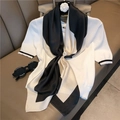 Detalle de un elegante pañuelo de seda a rayas anudado en un suéter de punto blanco - Negro y Beige