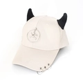 Detail of cream baseball cap featuring black devil horns and silver metal ring charms - Skull Beige