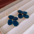 Dettaglio di orecchini a petalo blu scuro con ganci dorati in un portagioie beige - Gancio per Orecchio-Blu