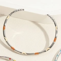 Detail van een zilveren open armband met oranje en beige emaille stippen op steenbasis - Maan Emaille Armband Stijl (SL0194-3)