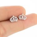 Minimalist silver stainless steel crown cross stud earrings shown in a hand-held macro view - Crown Cross / Steel