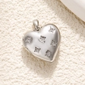 Macro shot of silver heart pendant with diamonds on a textured beige surface - Silver Micro-set Heart