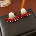 Dettaglio di orecchini dorati con perle bianche e nappe di perline rosse lucide - Ago in Argento - Oro (Placcato Oro Vero)