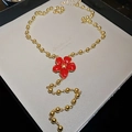 Dettaglio di una lunga collana a sfere dorate con un ciondolo a fiore rosso a cinque petali - Fiore Rosso (Oro-Rosso)