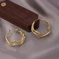 Chic twisted double-layer wavy gold hoop earrings on a luxury satin background - Wavy Earrings / E-061---Gold