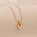 Collar dorado con colgante de corazón rosa en fondo beige, diseño minimalista de estilo francés - Rosa
