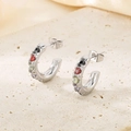 Detail view of silver C-shaped earrings with colorful inset gemstones on beige stone plate - Steel Multi-color Gemstone Style (KE116219-KFC)